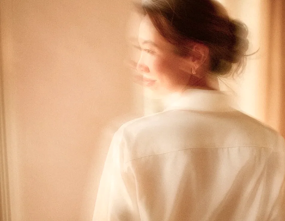 Woman in a white shirt smiling in soft sunlight